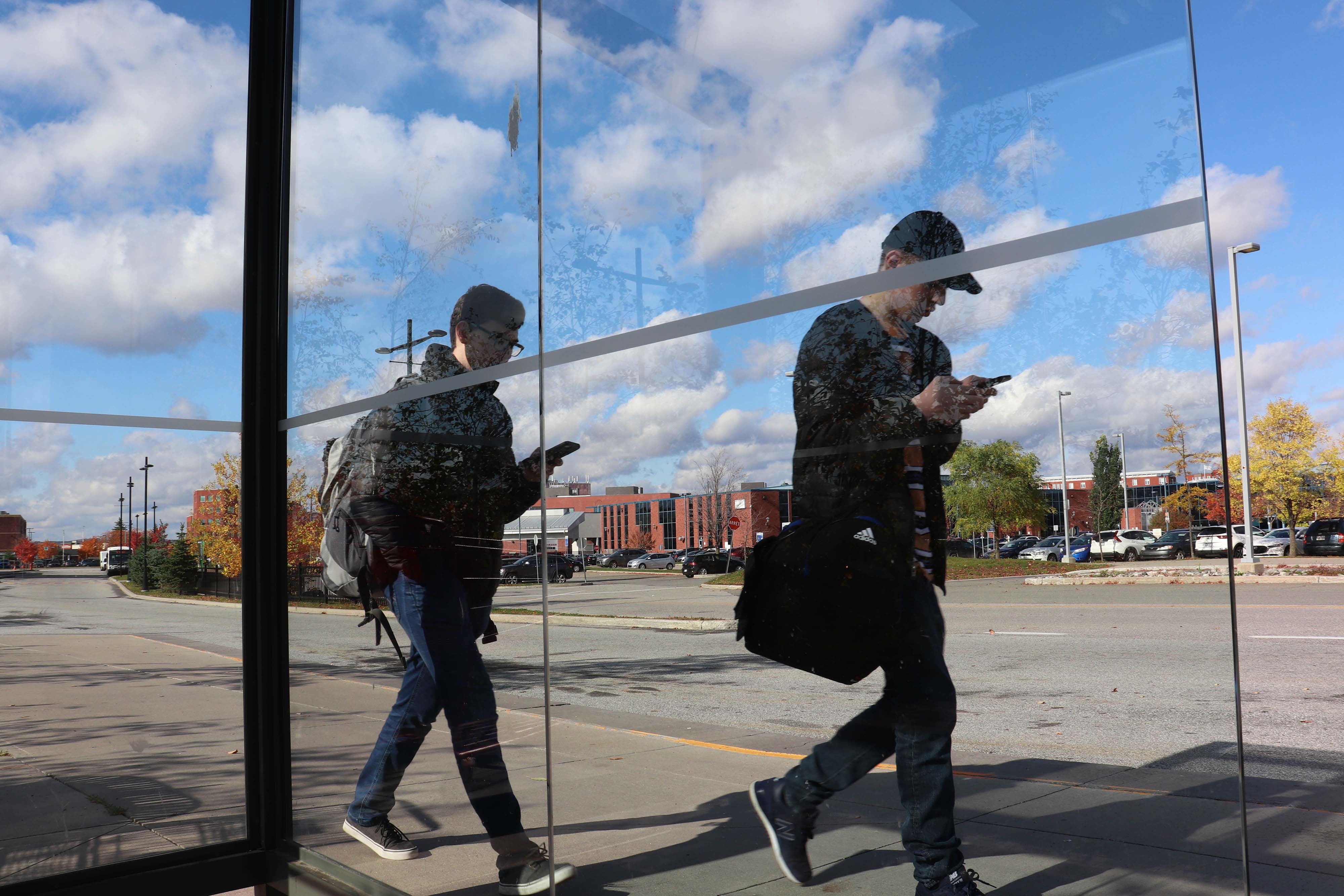 deux personnes marchant en regardant leurs cellulaires