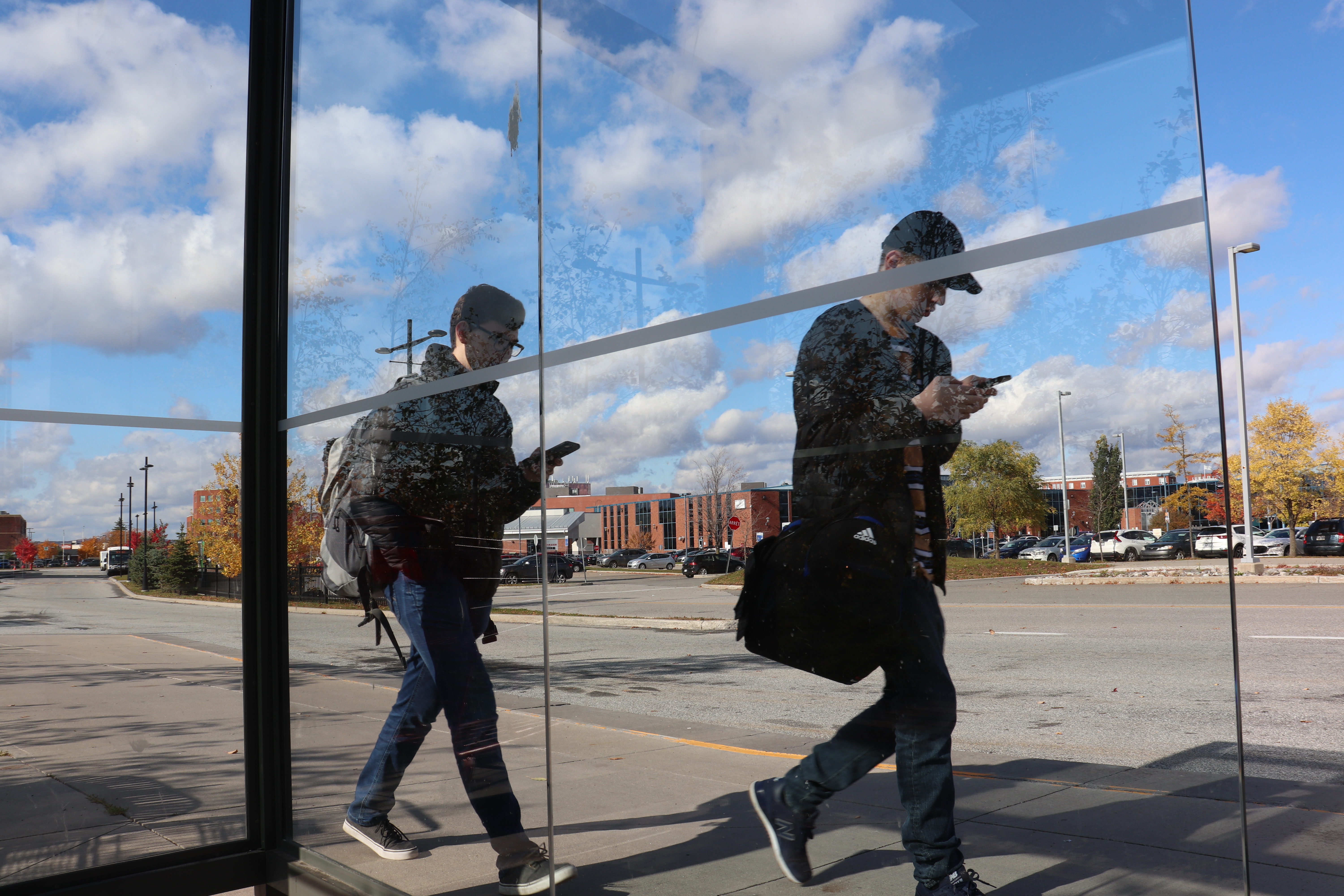 deux personnes marchant en regardant leurs cellulaires